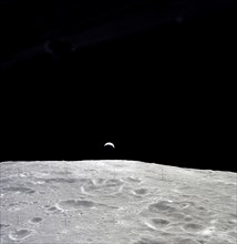 Earth rises above the lunar horizon as seen from Apollo 12 in lunar orbit