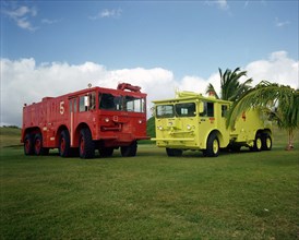 1977 - A left front view of a new lime-colored fire engine used at the base.  On the left is the old-style fire engine.
