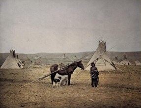 An Indian woman with her Indian pony in front of the tipis of an Indian village in the region Alberta
