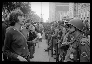 Young hippie standing in front of National Guard soldiers