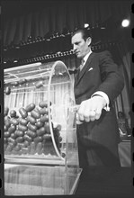 Curtis W. Tarr, director of the Selective Service System, turns the drum containing capsules of draft numbers at the annual draft lottery. Washington, DC, 2/2/1972. Thomas O' Halloran, photographer.