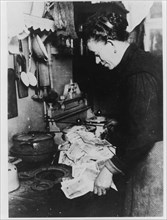 Berlin woman shown starting the morning fire with almost worthless German marks, Berlin, Germany, circa 1924.