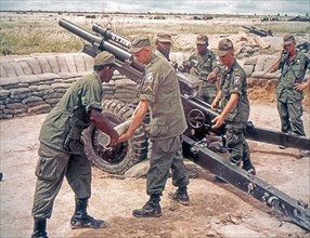 Members of the 173rd Airborne Division load a 105mm howitzer. Vietnam, 5/65.