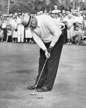 Sammy Snead sinks a putt to beat Tommy Bolt on the first hole of a playoff for the Miami Open Golf Tournament title. Miami, FL, 12/14/55.