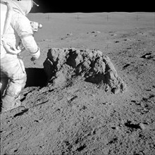 Astronaut Alan Shepard stands beside large boulder found by Apollo 14 crew