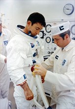 A technician attaches hose from test stand to spacesuit