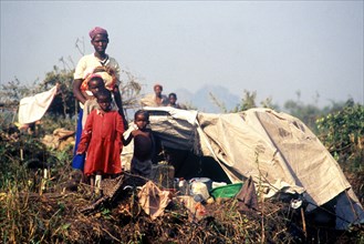 1994 - A Rwandan family pose in front of their makeshift home