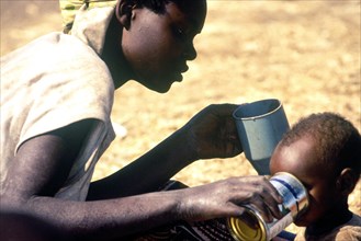 A Rwandan mother gives her child a drink of water