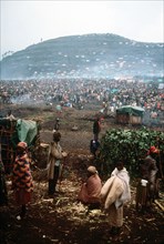 1994 - A group of refugees with the refugee camp in the background.