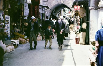 Customers walk among shops in the old part of a city (Israel 1960s street scene)