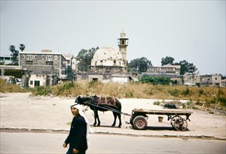 Arab man walking down road in Tiberias with cart in background