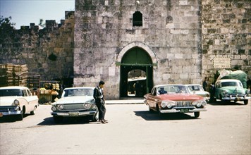 Man leaning against a car, in a parking lot, near the Damascus Gate in Jerusalem