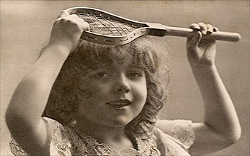 Young girl holding very little tennis racquet.