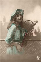 Woman in blue dress with Tennis Racquet and ball.