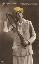 Woman in coat and hat with tennis racquet.