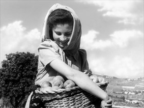 woman with small basket of peaches, 1950-1960