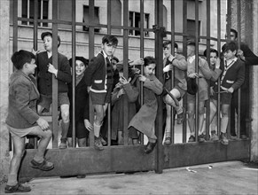 italie, lombardie, milan, à travers les barreaux des portes, des jeunes entrent gratuitement dans la XXIVe édition de la foire, 1951