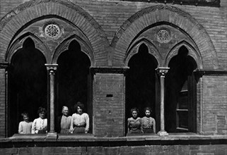 europa, italia, toscana, san gimignano, donne affacciate alle bifore di palazzo pratellesi, 1900 1910