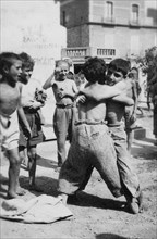 italie, basilicate, lavello, jeux de lutte entre enfants dans la rue, 1930