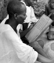 africa, ghana, giovane dagomba mentre legge il corano, 1930
