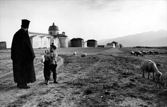 europa, italie, calabre, frascineto, moine basilien avec enfant près de l'église, 1965
