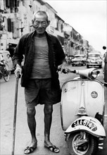 malaisie, singapour, un vieil homme à côté d'une moto italienne, 1968
