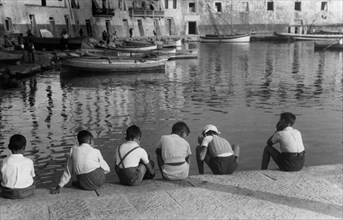 toscane, livourne, portoferraio, enfants assis sur le bord de la jetée, 1930