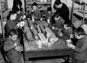 Italy. Rome. refuge for minors. orphans shape the clay and paint doll heads. 1949