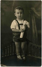 The little boy in shorts standing on a bench.