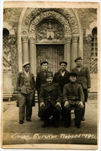 Group of men posing against the backdrop of a historic building.
