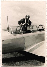 Pilot in a helmet standing in front of the cockpit of military aircraft.