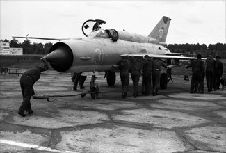 Mechanics roll aircraft MiG-21 on parking.