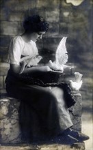 Woman sitting on stone steps, feeding white doves.