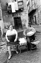 Woman selling chestnuts in an alley in Naples, Italy, 1977