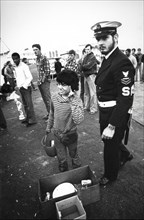 Little boy street vendor near an american soldier of saratoga aircraft carrier, 80's