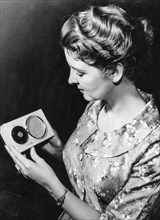 A woman with a powered by solar energy portable radio, 1957