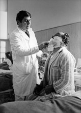 Barber shaves a patient of the San Giovanni hospital, Rome, 70s