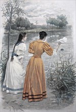 Two Women Are Waiting For Their Dog Swimming In The Lake