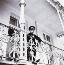 Tsarevich Alexei Nikolaievich of Russia stands on the banister of Alexander Palace's Balcony
