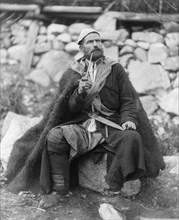 Old peasant with dagger and long smoking pipe