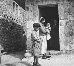 A Boy, lady And Baby In Isreal Outside an Old House.
