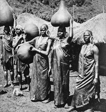 African tribes women with water pots on their geads in the local village.