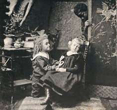 A boy and a girl with a black man looking on from behind a screen.