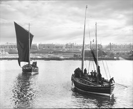 Fishing boats leaving harbour with South Shields town in the background.