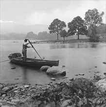 A man punting a rowing boat on Lake Windermere.