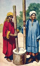 Indian women pounding rice.