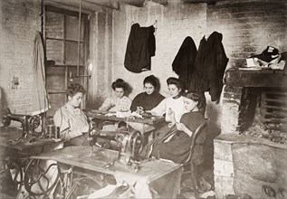 Five young seamstresses working for a starvation wage in a New York tenement sweat shop.