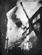 London's fire fighting service directing streams of water from soaring fire ladders and ground vantage points on to a blazing business fire.
