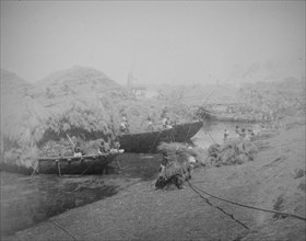 Riverbank showing boats being loaded with straw or reeds
