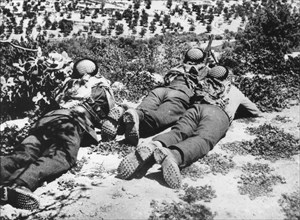 Three Arab soldiers lying on the ground overlooking a valley in Palestine.  They are guarding against attacks from Jewish soldiers.